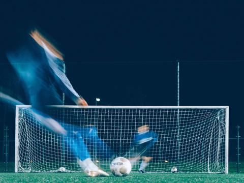 Blurred time lapse image of a striker taking a penalty spot kick