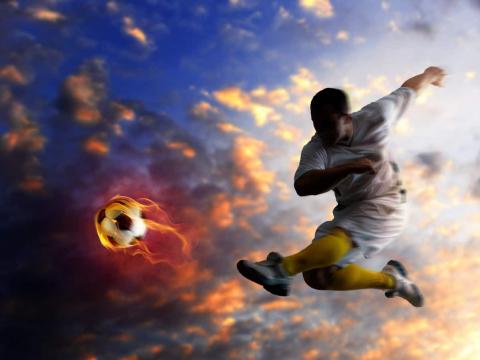 Young soccer player kicking a flaming football